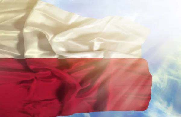 Poland waving flag against blue sky with sunrays — Stock Photo, Image