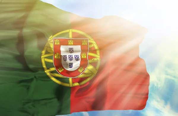 Portugal schwenkt Flagge gegen blauen Himmel mit Sonnenstrahlen — Stockfoto