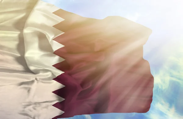 Qatar zwaaien vlag tegen blauwe hemel met zonnestralen — Stockfoto