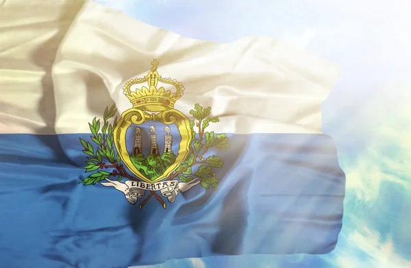 San Marino ondeando bandera contra el cielo azul con rayos de sol — Foto de Stock