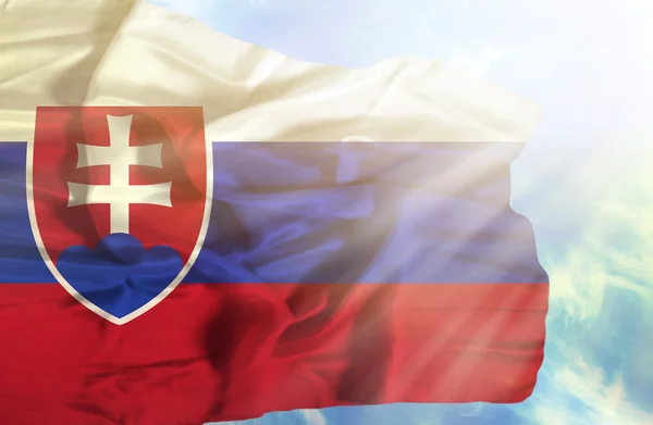 Slovakien viftande flagga mot blå himmel med solstrålar — Stockfoto