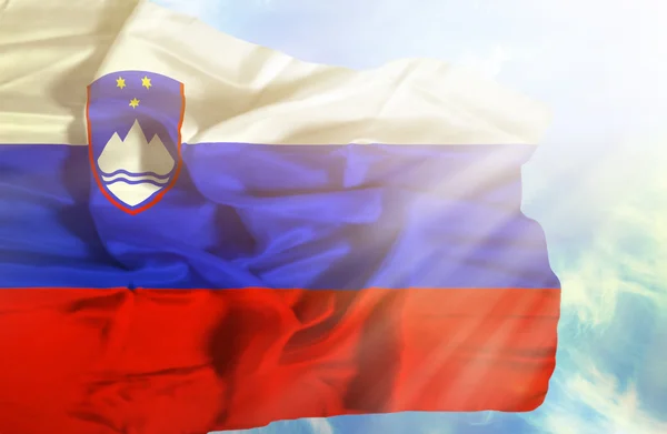 Slovenië zwaaien vlag tegen blauwe hemel met zonnestralen — Stockfoto