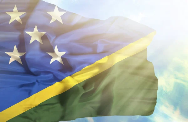 Solomon Islands waving flag against blue sky with sunrays — Stock Photo, Image