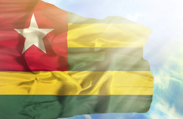 Togo ondeando bandera contra el cielo azul con rayos de sol —  Fotos de Stock