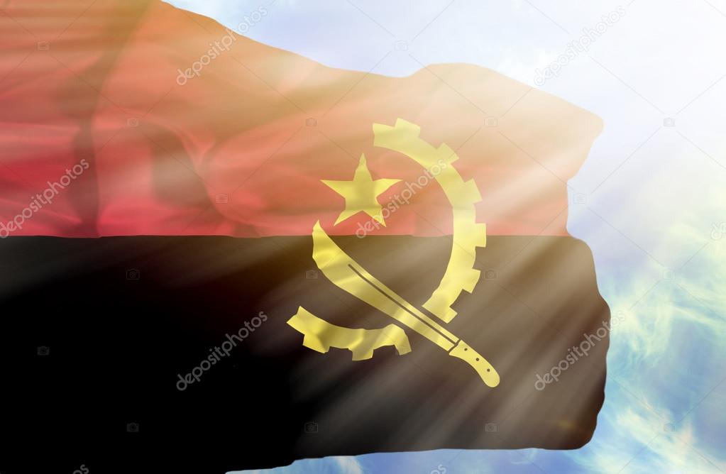Angola waving flag against blue sky with sunrays