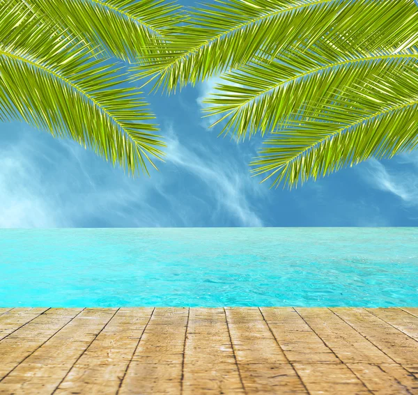 Schöner tropischer Strand mit Holzboden und Palmenblättern — Stockfoto