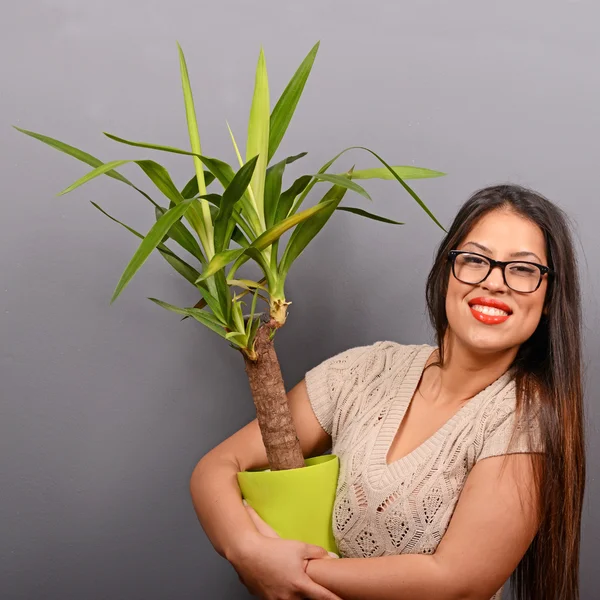 Mooie gelukkige vrouw houden plant in vaas tegen grijs backgro — Stockfoto