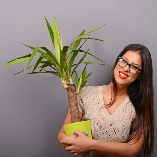 Mooie gelukkige vrouw houden plant in vaas tegen grijs backgro — Stockfoto