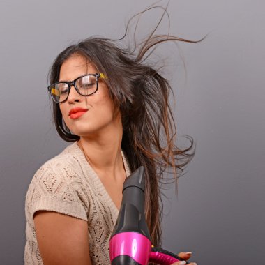 Saç kurutma makinesi gri bir arka plana dayanır tutan bir kadın portresi