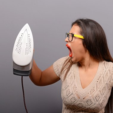 Portrait of woman shouting at iron and tired of house work again clipart