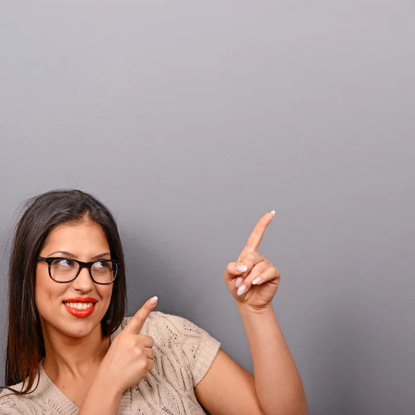 Mulher bonita apontando para área em branco contra fundo cinza — Fotografia de Stock