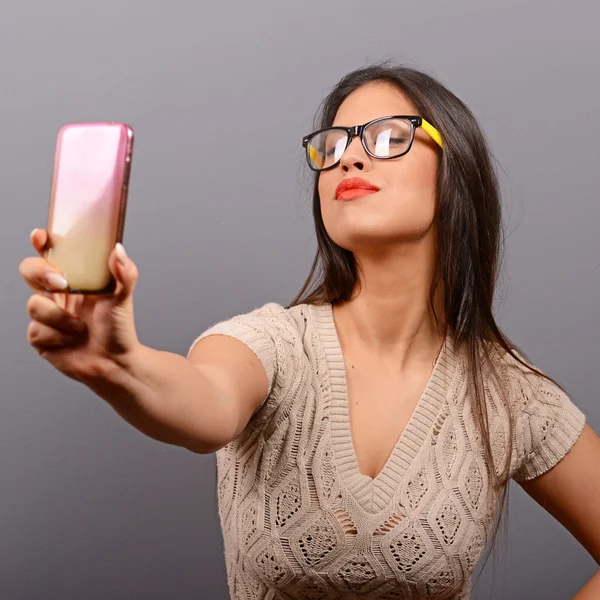 Retrato de una chica tomando selfie con teléfono celular contra bac gris — Foto de Stock