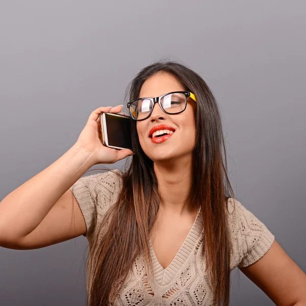 Portrait of a happy young woman talking on a cellphone against g — Stock Photo, Image