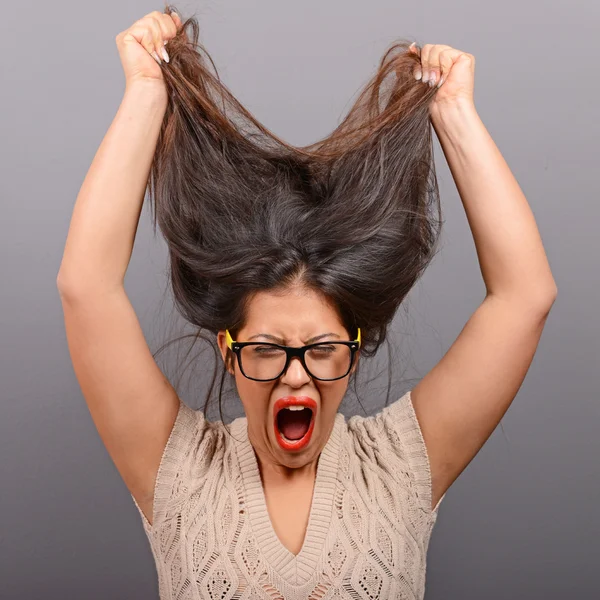 Portret van een vrouw van de histerical trekken van haren uit tegen grijze bac — Stockfoto