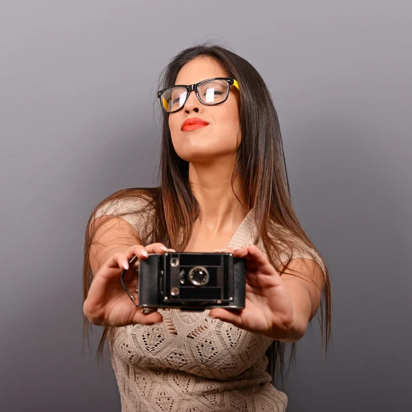 Ritratto di una giovane donna che tiene una fotocamera retrò contro la schiena grigia — Foto Stock