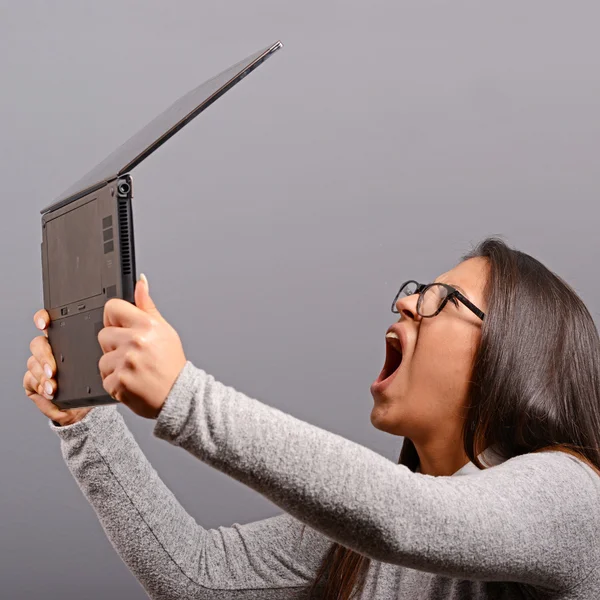 Портрет злой женщины, кричащей на свой ноутбук против серой Ба — стоковое фото