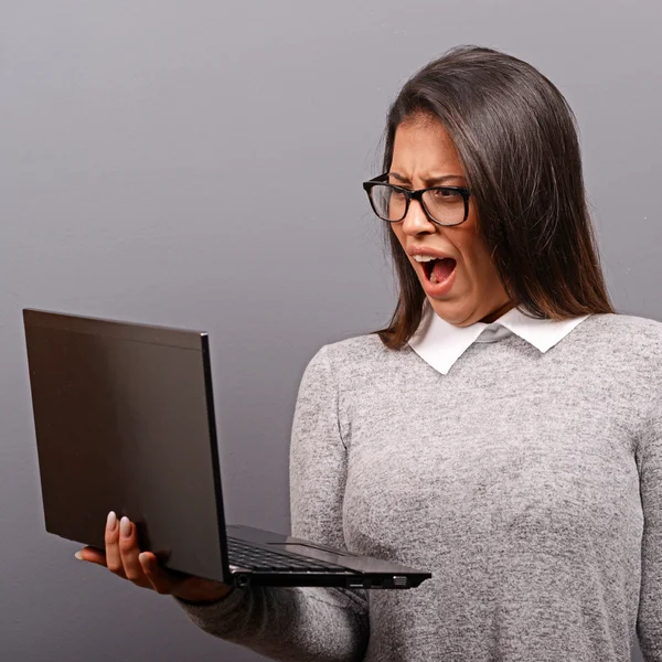 Porträt einer wütenden Frau, die an ihrem Laptop gegen grauen Ba schreit — Stockfoto