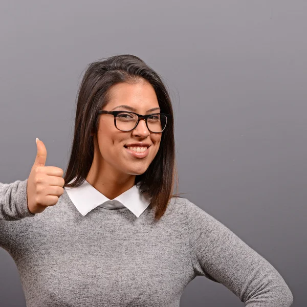 Retrato de mujer feliz sosteniendo pulgares contra fondo gris — Foto de Stock