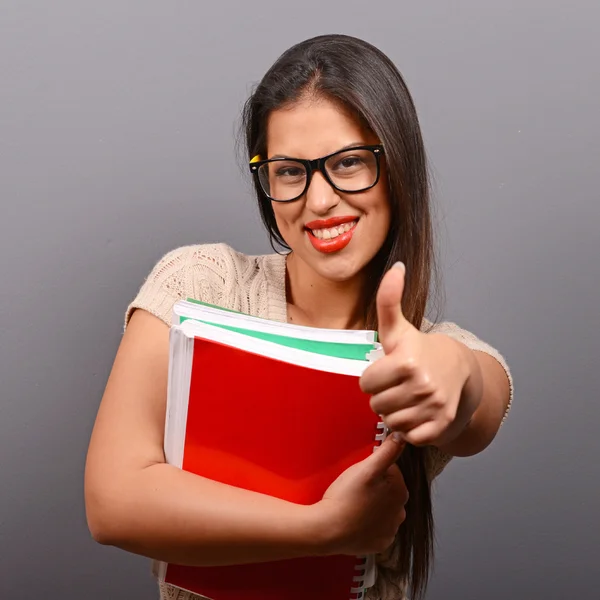 Portrait of happy student woman holding books with thumb up agai — Stock Photo, Image