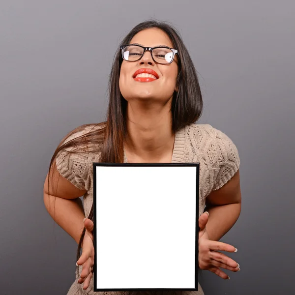 Portrait of smiling woman holding blank photo frame against gray — Stock Photo, Image