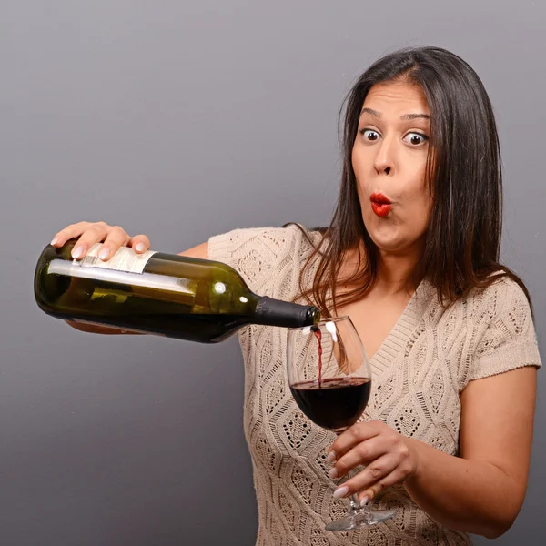 Portrait of woman holding wine bottle and glass against gray bac — ストック写真