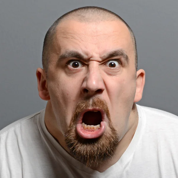 Портрет злого человека, кричащего на сером фоне — стоковое фото