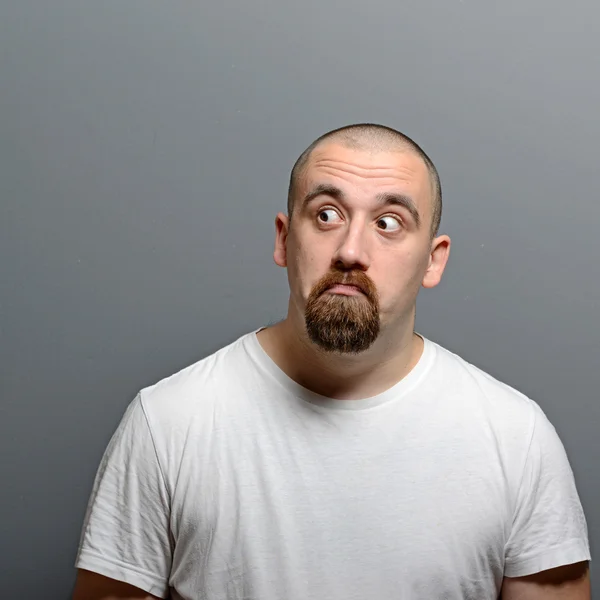 Portræt af en forvirret mand på grå baggrund - Stock-foto
