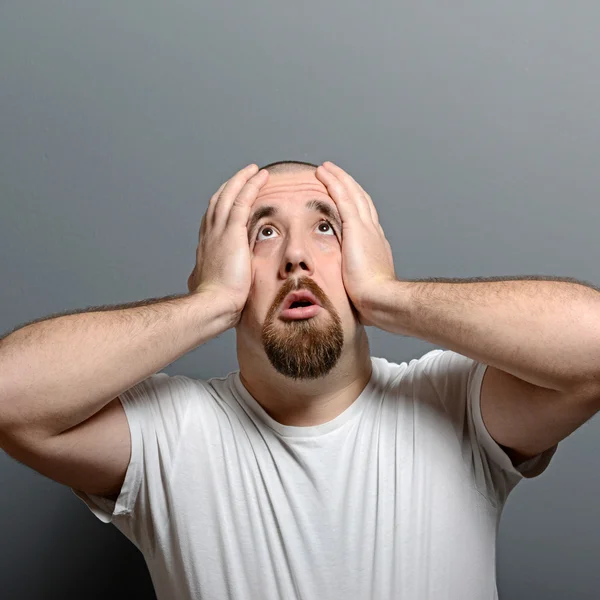 Portrait of a desperate man in shock against gray background — Stock Photo, Image