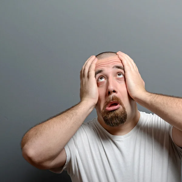 Portrait of a desperate man in shock against gray background — Stock Photo, Image