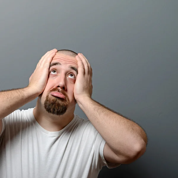 Portret van een wanhopige man in schok tegen de grijze achtergrond — Stockfoto