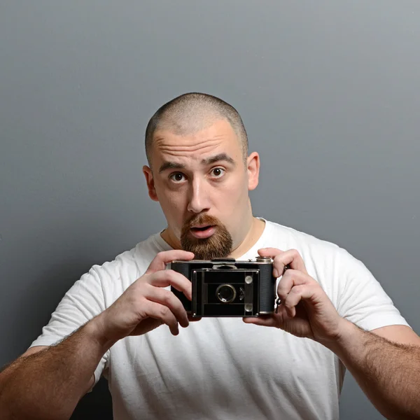 Retrato de un hombre sosteniendo cámara retro sobre fondo gris —  Fotos de Stock