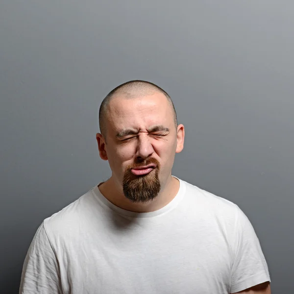 Porträt eines Mannes mit lustigem Gesicht vor grauem Hintergrund — Stockfoto