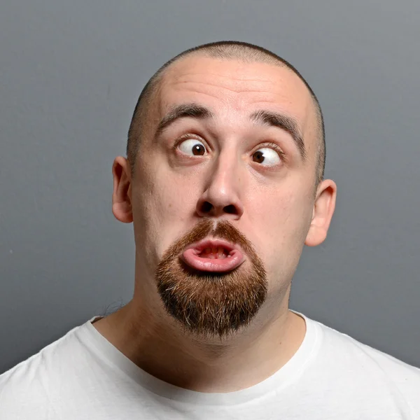 Retrato de un hombre haciendo cara graciosa sobre fondo gris —  Fotos de Stock