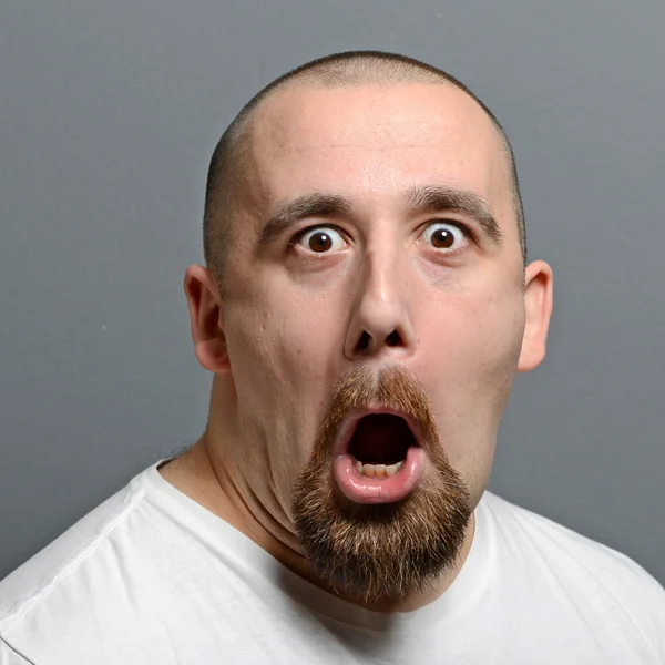 Portret van een man die grappig gezicht tegen de grijze achtergrond — Stockfoto