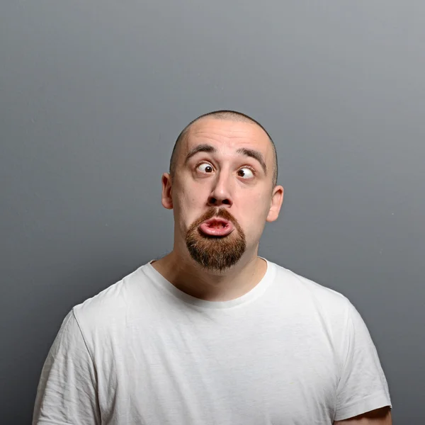 Портрет человека, делающего смешное лицо на сером фоне — стоковое фото