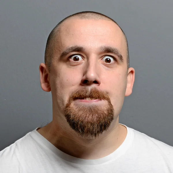 Retrato de un hombre haciendo cara graciosa sobre fondo gris —  Fotos de Stock