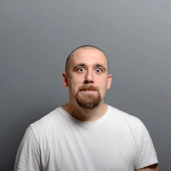 Porträtt av en man att göra roliga ansikte mot grå bakgrund — Stockfoto