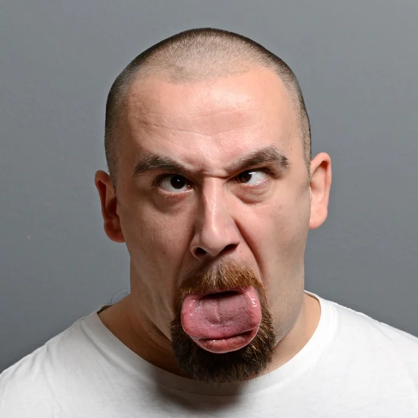 Retrato de un hombre haciendo cara graciosa sobre fondo gris —  Fotos de Stock