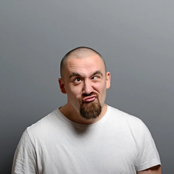 Портрет человека, делающего смешное лицо на сером фоне — стоковое фото
