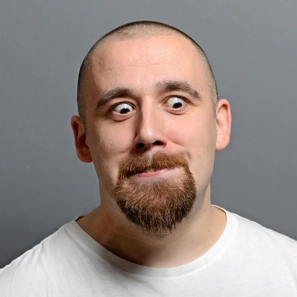 Retrato de un hombre haciendo cara graciosa sobre fondo gris —  Fotos de Stock