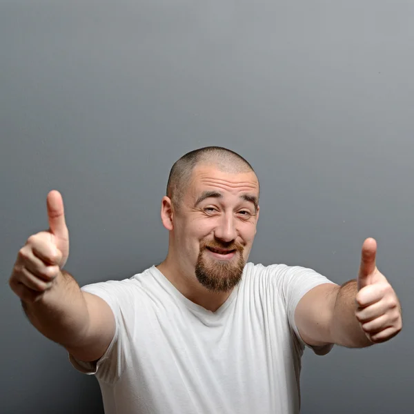 Portrét muže ukazuje palcem nahoru nebo ok znamení proti šedé pozadí — Stock fotografie