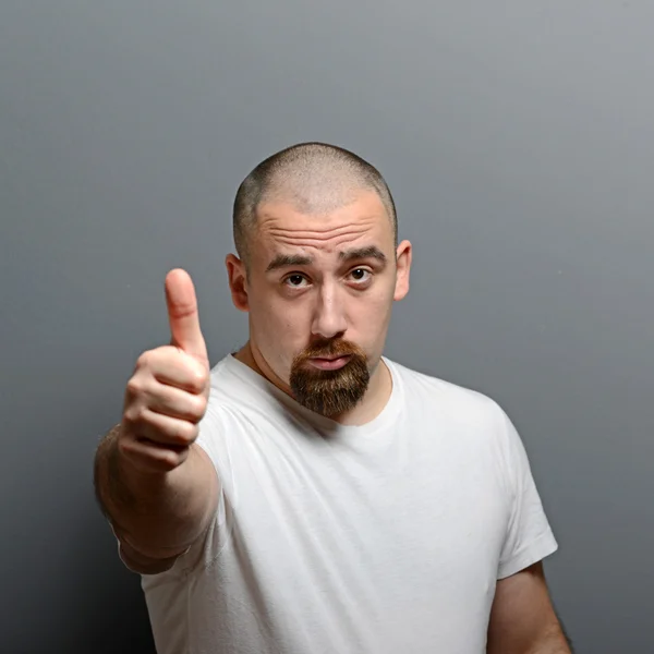 Portrait of a man showing thumb up or ok sign against gray backg — Stock Photo, Image