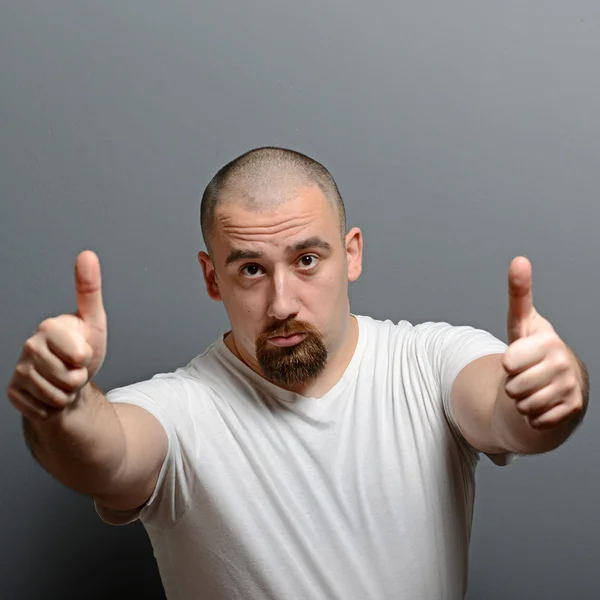 Retrato de un hombre mostrando el pulgar hacia arriba o signo de ok contra la espalda gris —  Fotos de Stock