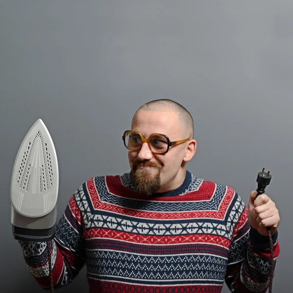 Portrait of a nerdy man holding iron against gray background — Stock Photo, Image