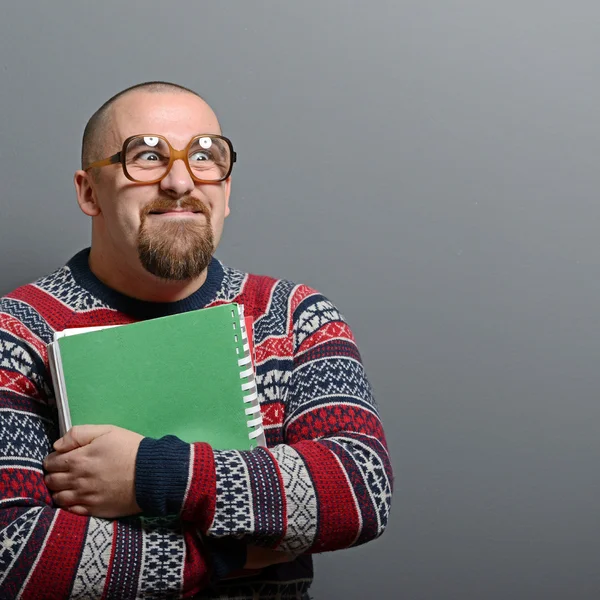 Portrait of a nerd holding book with retro glasses against gray — Stock Photo, Image