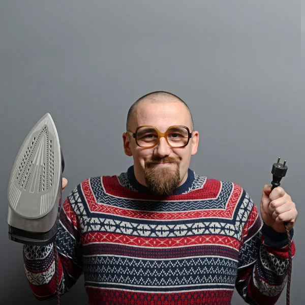 Retrato de um homem nerd segurando ferro contra fundo cinza — Fotografia de Stock