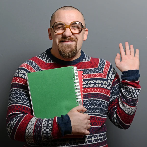 Portrait of a nerd holding book with retro glasses against gray — Stock Photo, Image
