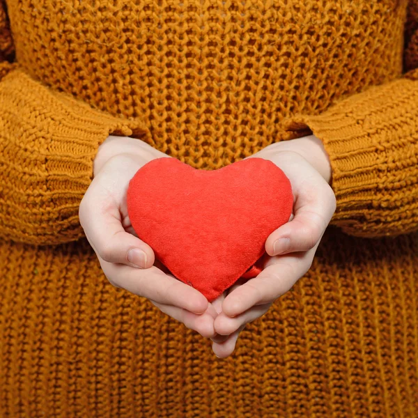 Beautiful happy woman holding heart in hands against gray backgr — Stock Photo, Image