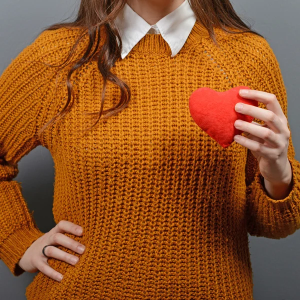 Hermosa mujer feliz sosteniendo el corazón en las manos contra gris backgr — Foto de Stock