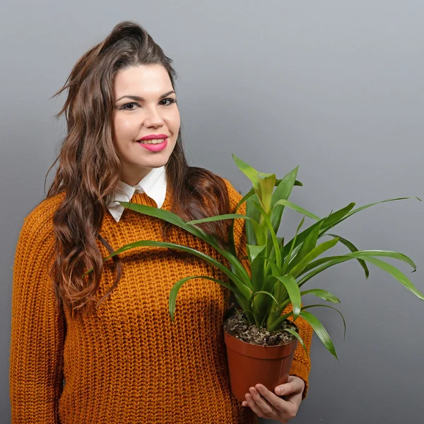 Mooie gelukkige vrouw houden plant in vaas tegen grijs backgro — Stockfoto